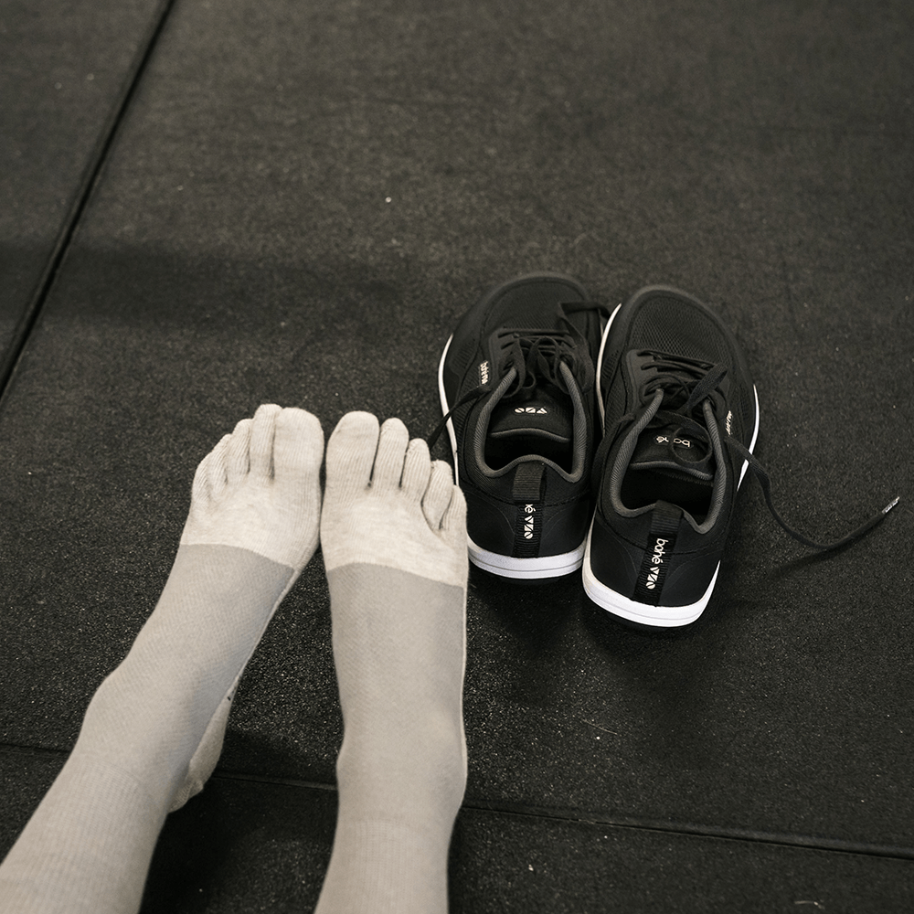 someone wearing bahé toe socks in the gym, with a pair of Bahé modes to the right of her feet.