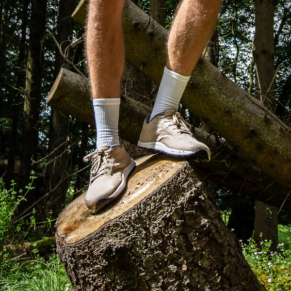 Bahé Revive barefoot style shoe in Sandstone (beige) on a man standing on log