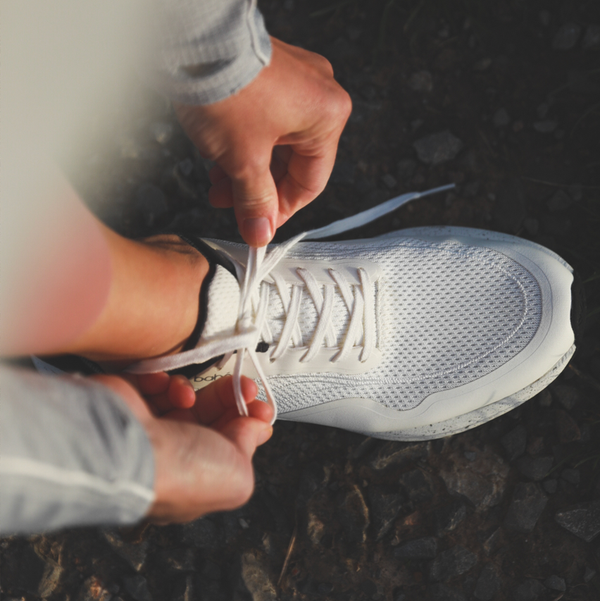 Bahé Recharge grounding shoes in Frost (white) worn by woman tying laces