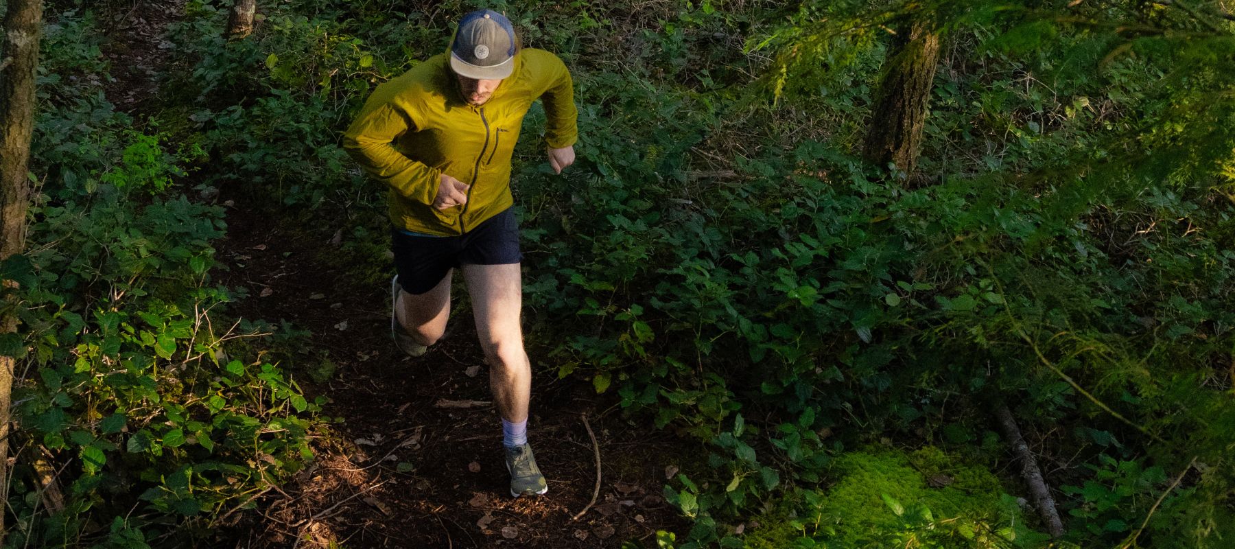 Person running on a rocky trail wearing green running shoes and white socks.