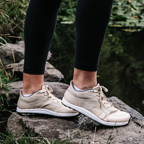 Woman wearing Bahé Revive barefoot style grounding shoe (Sandstone - beige) in nature