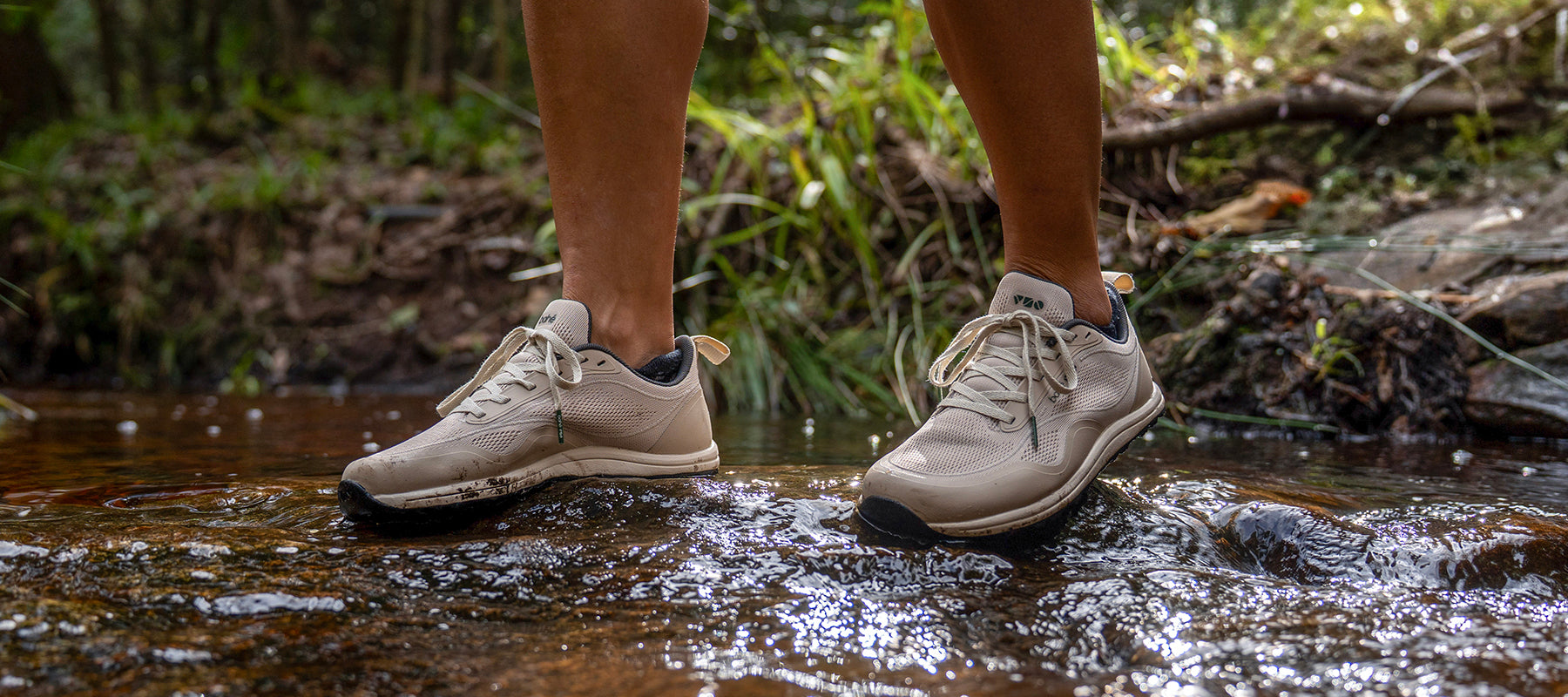 Person wearing Modes while crossing a river, they are standing on a rock