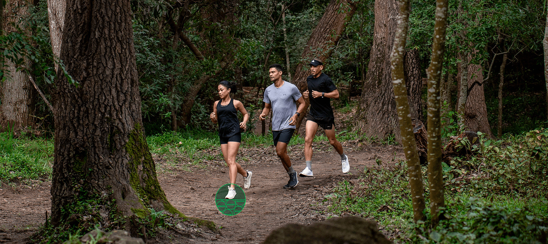 Three people running on a trail in a forest in Bahé grounding shoes