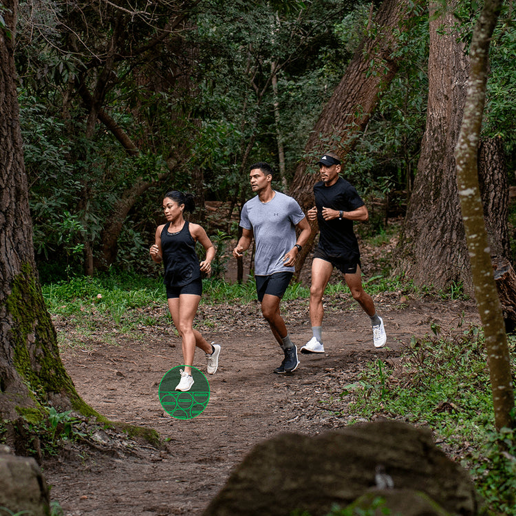 Three people running on a trail in a forest in Bahé grounding shoes