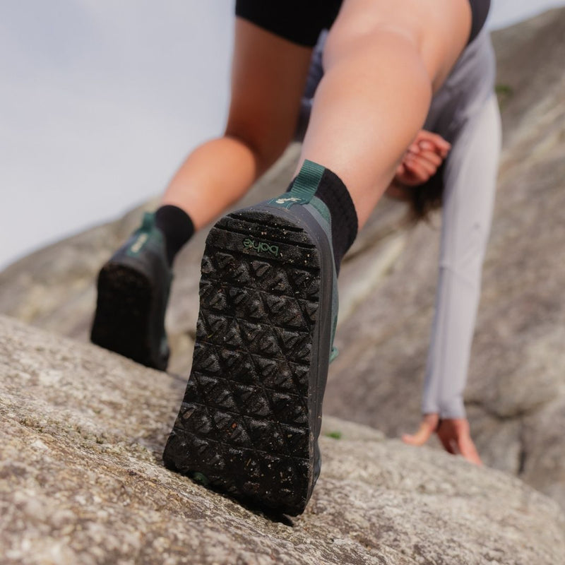 Person wearing Bahé shoes on a rocky surface
