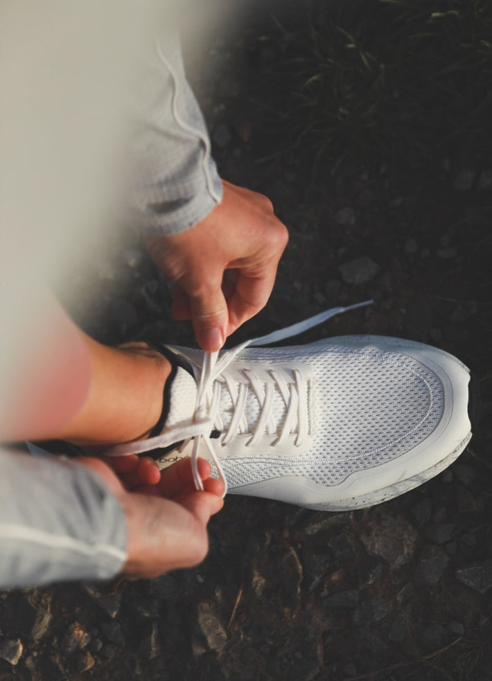 Aerial of woman tying Bahé Recharge frost grounding shoes