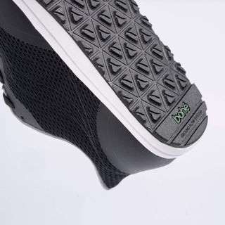 Close-up of a black shoe with textured sole on a light gray background