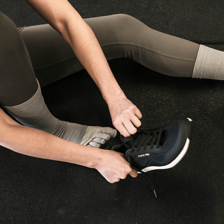 Woman putting on Bahé Revive Flex Midnight Grounded Training Shoe