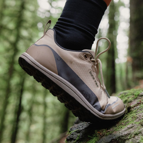 Beige hiking shoe on a person's foot with a forest background