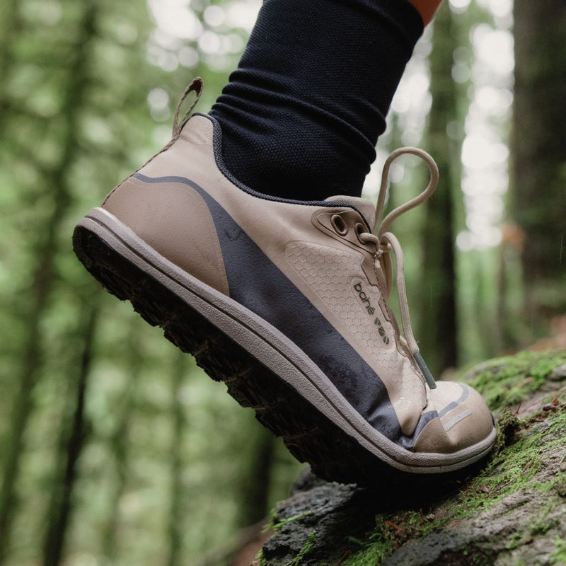 Beige hiking shoe on a person's foot with a forest background